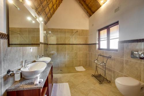 a bathroom with two sinks and a toilet and a shower at Kubu Safari Lodge in Hoedspruit