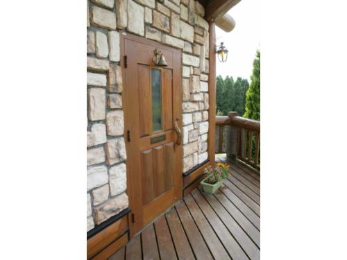 a wooden door on a porch with a stone wall at Log house for 12 people - Vacation STAY 33957v in Minamioguni