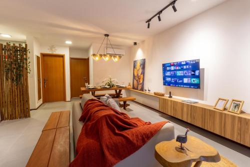 a living room with a couch and a tv at Villa Naluri - Seu Refúgio a 50 metros da praia em Japaratinga in Japaratinga