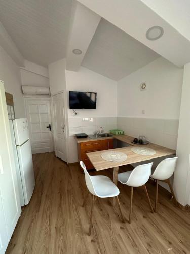 a kitchen with a wooden table and white chairs at Casa Adriana Cluj-Napoca in Cluj-Napoca