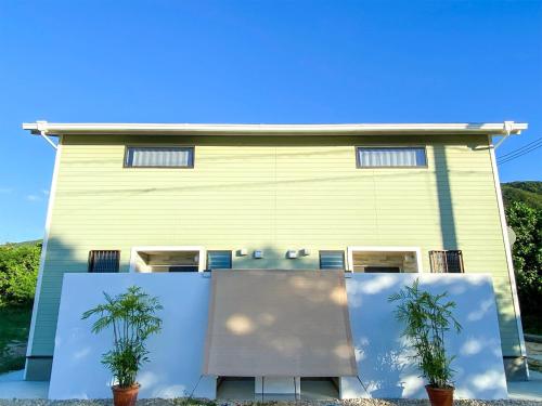a yellow house with two potted plants in front of it at Yonehara Beach Stay LUANA - Vacation STAY 38711v in Fukai