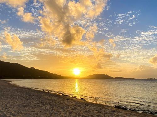 a sunset on a beach with the sun setting at Yonehara Beach Stay LUANA - Vacation STAY 38711v in Fukai