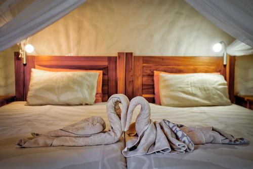 two towel swans sitting on top of a bed at Kubu Safari Lodge in Hoedspruit