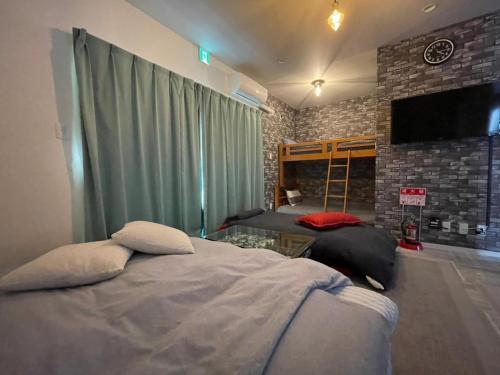 a bedroom with a bed and a tv and a brick wall at Hotel Yua - Vacation STAY 40741v in Nago