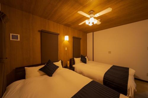 a bedroom with two beds and a ceiling fan at Tabi no yado Hanakeshiki Nanohana 1st floor - Vacation STAY 42962v in Yufuin