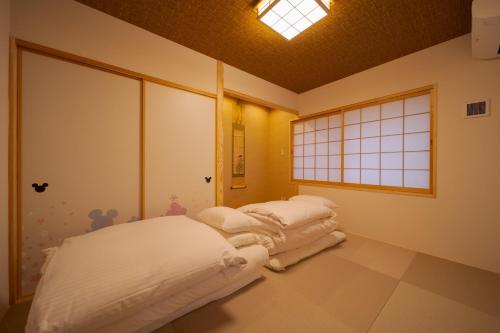 two beds in a room with a window at Tabi no yado Hanakeshiki Nanohana 1st floor - Vacation STAY 42962v in Yufuin