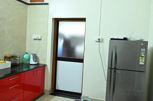 a kitchen with a refrigerator and a red cabinet at Anugraha Bed&Breakfast Homestay in Kumta