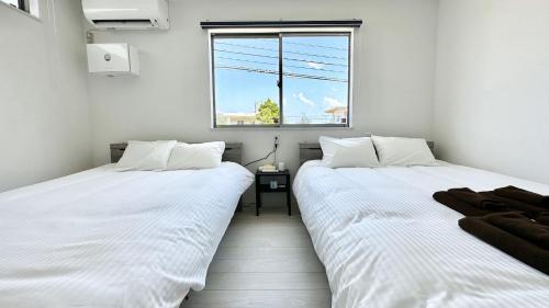 two white beds in a room with a window at Grandioso Onna 7-D - Vacation STAY 10524v in Atsutabaru
