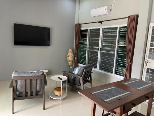 a living room with a table and chairs and a television at Khwanlom House in Lampang