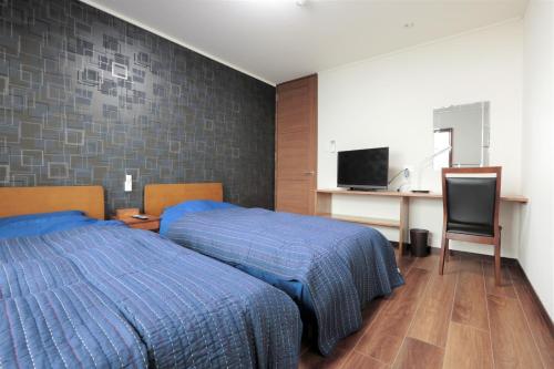 a bedroom with a bed and a desk and a television at ROYAL SUITE SAKAE - Vacation STAY 11483 in Nagoya