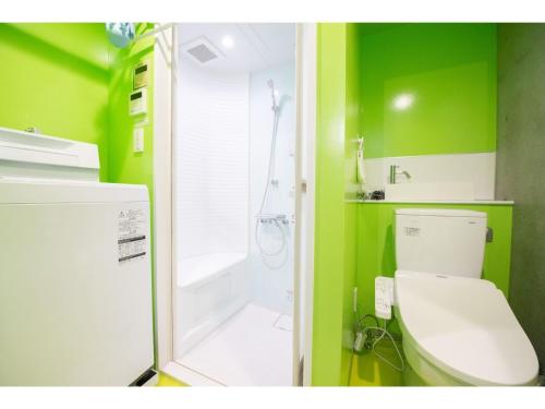 a green bathroom with a toilet and a shower at bmj Hyakunincho - Vacation STAY 46879v in Tokyo