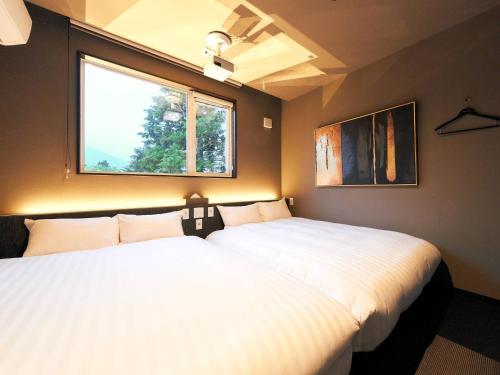 zwei Betten in einem Zimmer mit Fenster in der Unterkunft Rakuten STAY VILLA Hakone Sengokuhara North Wing 102 with Massage chair, capacity of 10 persons in Hakone