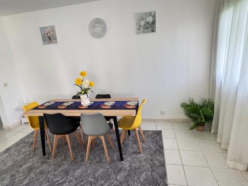 a dining room table with chairs and a vase of flowers at Charmant T2 Lumineux Spacieux Vieux Cocody Centre in Abidjan