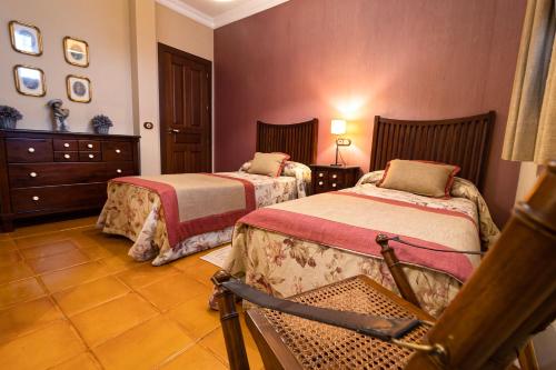 ein Schlafzimmer mit 2 Betten und einem Stuhl darin in der Unterkunft Hacienda los Manchones in Puente-Genil