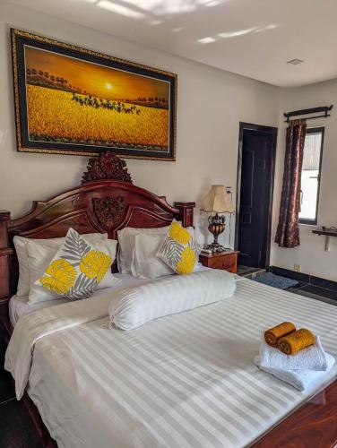 a bedroom with a large bed with yellow and white pillows at Travellers Inn in Phumĭ Réach Born