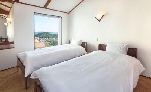 two beds in a room with a large window at Bay Coast Villa Kisami - Vacation STAY 33529v in Shimoda