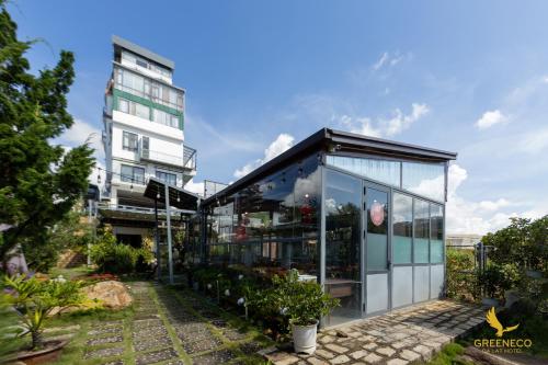 a glass house in a garden with a tall building at GREENECO DA LAT HOTEL - Khách sạn Green Eco Đà Lạt in Da Lat
