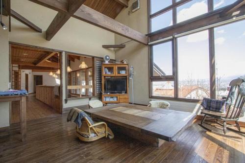 a living room with a wooden table and some windows at Sanso Harunoki staff-resident type - Vacation STAY 11615 in Furano