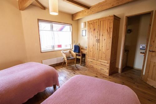a bedroom with two beds and a desk and a window at Sanso Harunoki staff-resident type - Vacation STAY 11615 in Furano