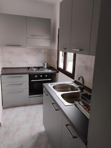 a white kitchen with a sink and a stove at Gorofai in Bitti