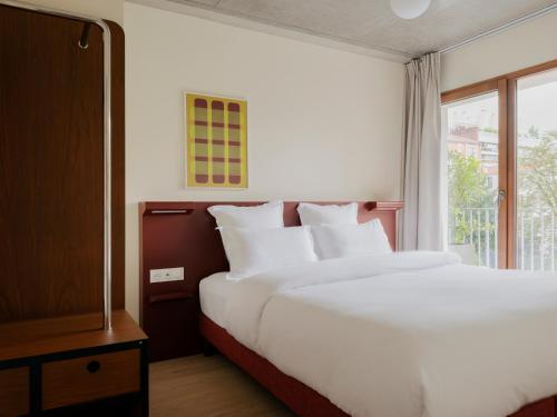 a large white bed in a room with a window at Edgar Suites - Église in Paris