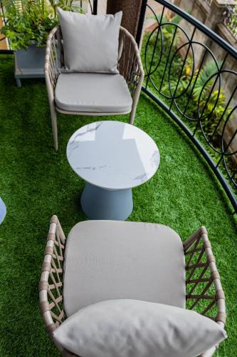 two chairs and a table on a balcony with grass at Pitta Opulent Apartments in Kampala