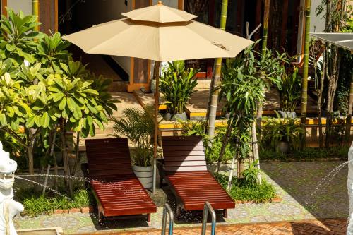 two chairs and an umbrella on a patio at Travellers Inn in Phumĭ Réach Born