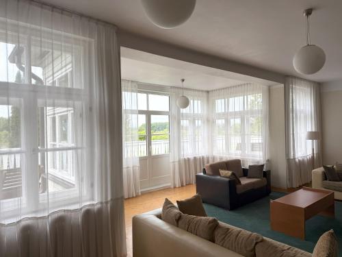 a living room with a couch and chairs and windows at Atpūtas komplekss "Ratnieki" in Ratnieki