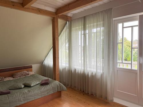 a bedroom with a bed and a large window at Atpūtas komplekss "Ratnieki" in Ratnieki