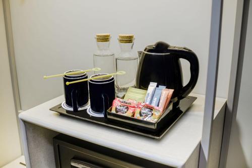 a tray with a tea kettle and other items on a shelf at Yello Hotel Samarinda in Samarinda