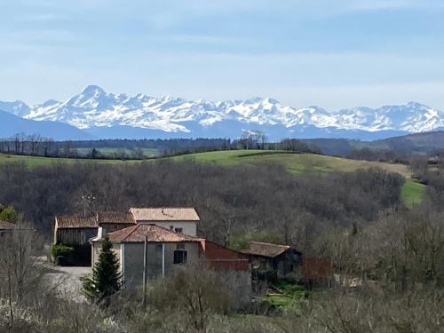 an old house in a field with mountains in the background at 85 m2 de plain-pied dans maison confortable avec vue sur la vallée et les Pyrénées ariégeoises, grande terrasse avec barbecue et parking gratuit in Castéras