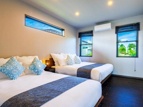 two beds in a room with two windows at Grace Villa Miyakojima - Vacation STAY 60494v in Uechi