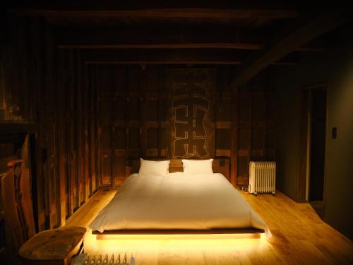 a bedroom with a large bed with white sheets at 岡の里旅籠塩屋 in Taketa