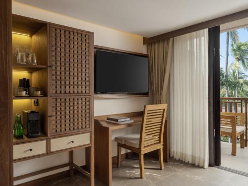 a hotel room with a desk and a television at Paradisus by Meliá Bali in Nusa Dua