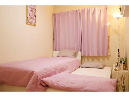 two beds in a room with pink sheets and a window at OHANA TOKYO HOUSE - Vacation STAY 73654v in Tokyo