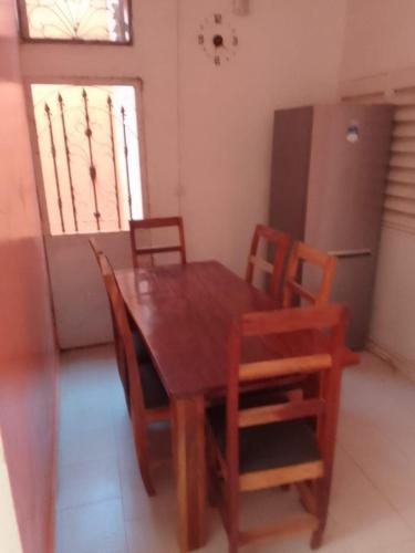 a wooden dining room table with chairs and a refrigerator at Accueil 1 in Rufisque