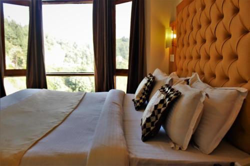 a bedroom with a bed with pillows and a window at Hotel Golf Links, Mashobra in Mashobra