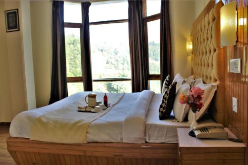 a large bed in a room with a large window at Hotel Golf Links, Mashobra in Mashobra