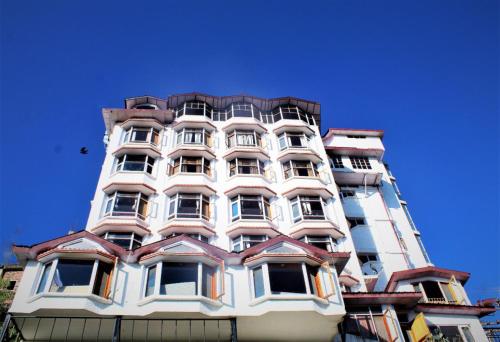 a tall white building with many windows at Hotel Golf Links, Mashobra in Mashobra
