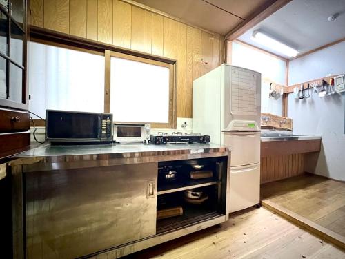 a kitchen with a counter with a microwave and a refrigerator at Kiyo's Gokokuen "Tatsumado" - Vacation STAY 77728v in Kasama
