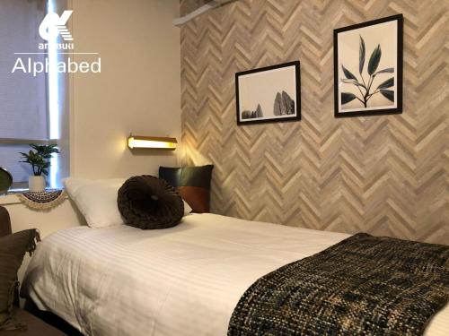 a bedroom with a white bed and a wall at Alphabed Takamatsu Furujinmachi - Vacation STAY 11907 in Takamatsu