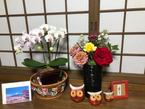 a table with two vases with flowers and some pictures at Fukurou no Oyado - Vacation STAY 71286v in Fuefuki