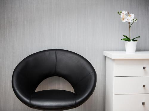 a black chair in a room with a vase of flowers at Softly Residence in Bydgoszcz