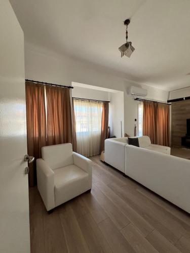 a living room with two white chairs and a couch at 3artı1 iki katlı daire in Aglantzia