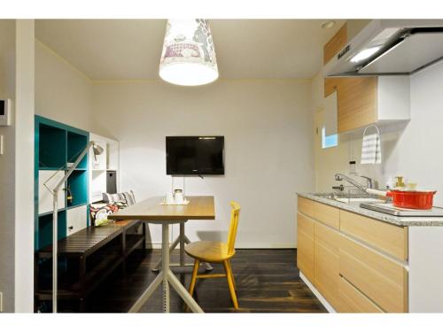 a kitchen with a table and a desk with a tv at Konpeitou House - Vacation STAY 11969 in Osaka