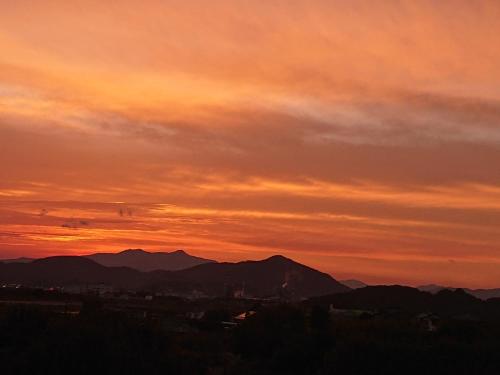 a sunset over a city with mountains in the background at ＬＯＤＧＥ ｎ"ｔｒｉｂｅ - Vacation STAY 08161v in Nichinan