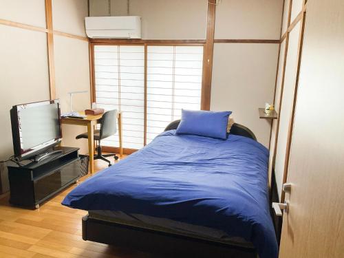 a bedroom with a blue bed and a television at Takayanagi Ryokan - Vacation STAY 88522v in Takamatsu