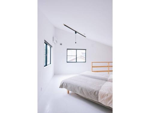 ein weißes Schlafzimmer mit einem Bett und zwei Fenstern in der Unterkunft Capetown Resort - Vacation STAY 96524v in Isumi