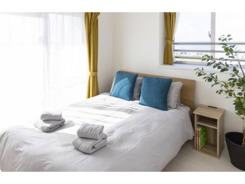 a bedroom with a white bed with blue pillows at Vent du Vent 5F - Vacation STAY 83698v in Urasoe