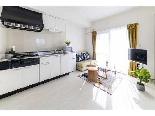 a kitchen with white cabinets and a living room at Vent du Vent 5F - Vacation STAY 83698v in Urasoe